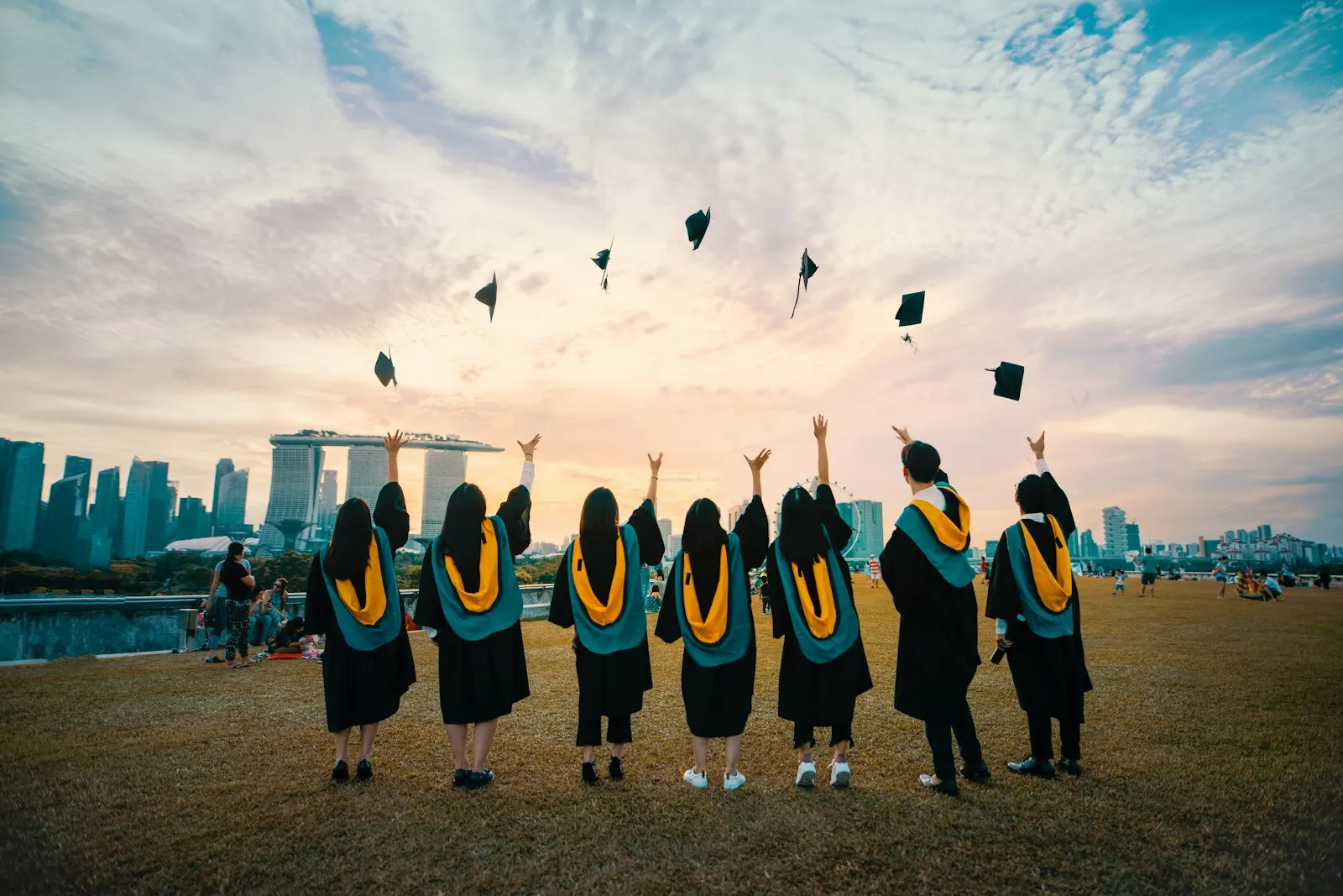 Graduates throw their caps into the sky above the Singapore skyline