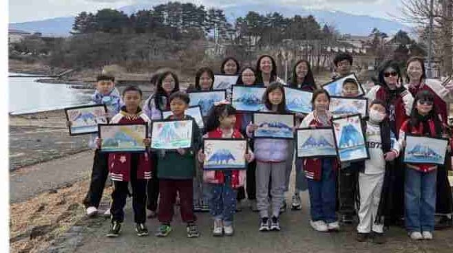 Students holding their Mount Fuji paintings by Lake Kawaguchi