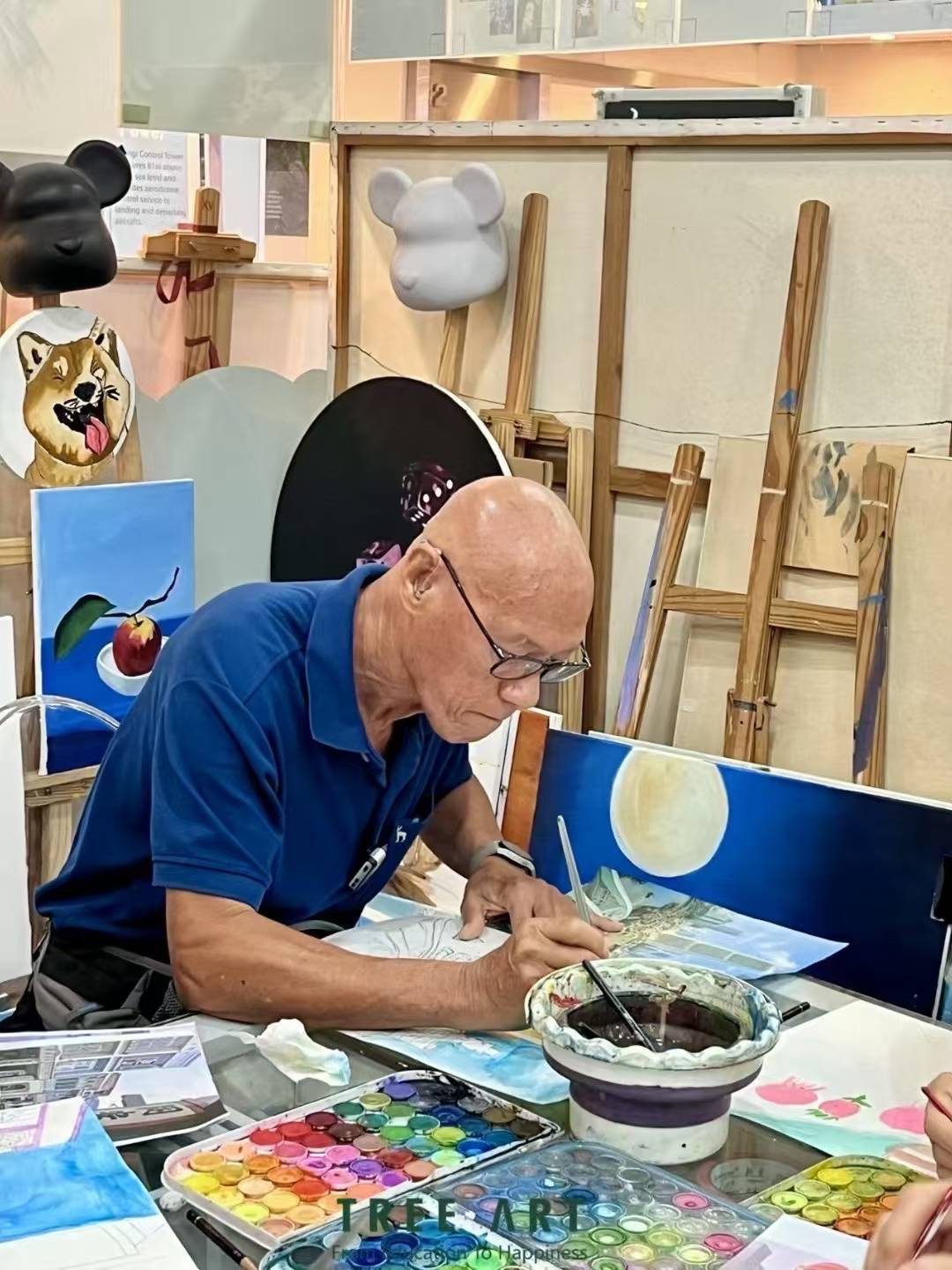 Senior student absorbed in painting from a photo reference at a Tree Art studio table