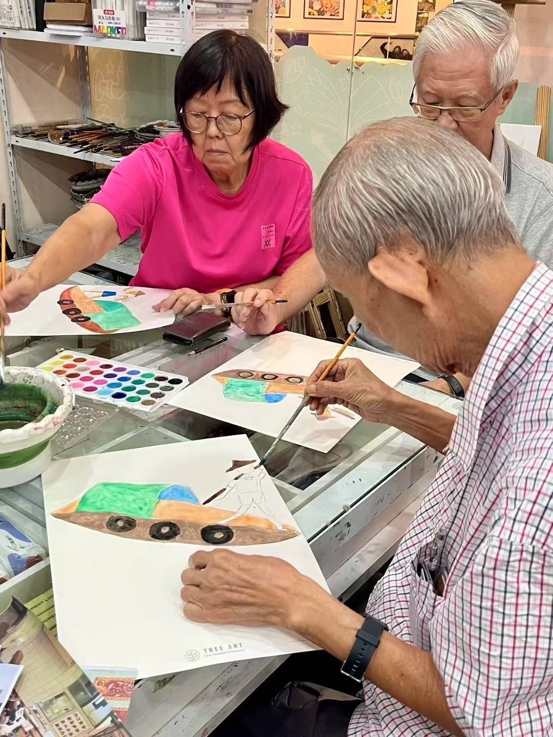 Three senior students painting watercolour boat scenes at a Tree Art studio table