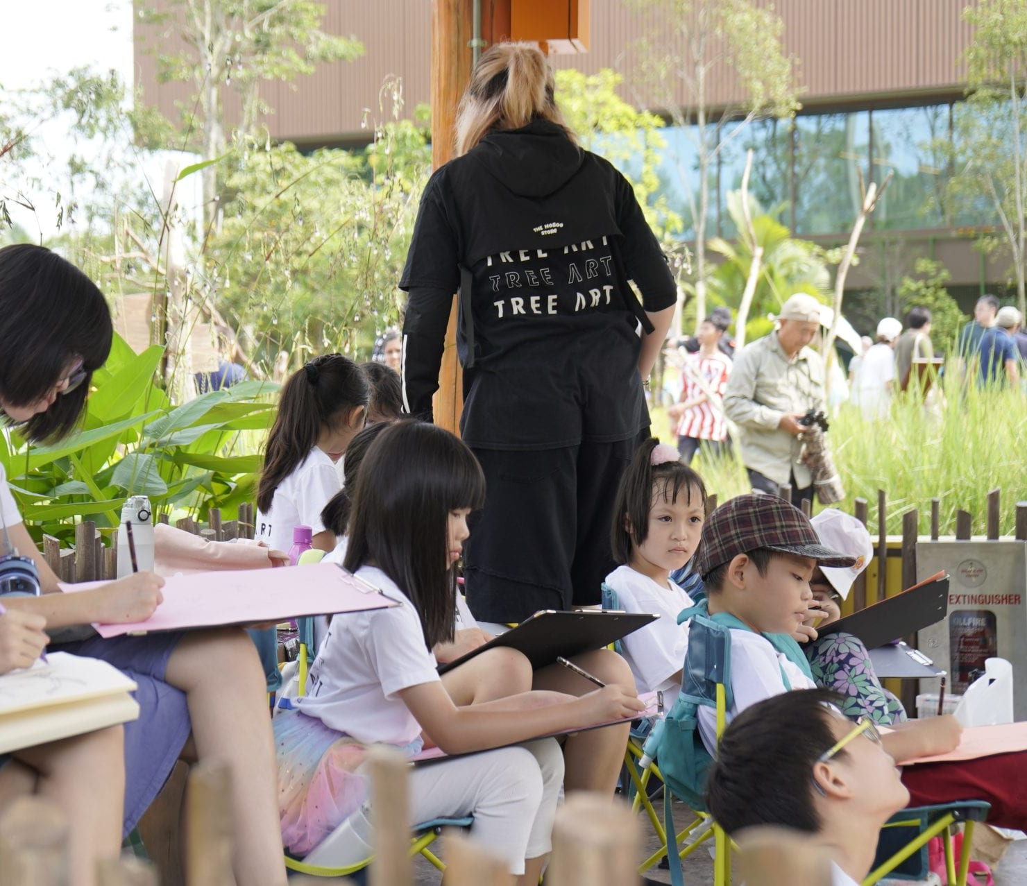 Children sketching on clipboards during an outdoor TREE ART drawing session