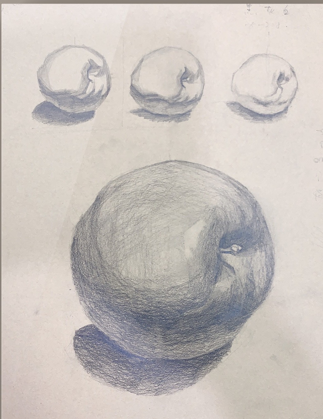 Pencil study sheet of an apple in three tonal steps above a finished shaded apple drawing