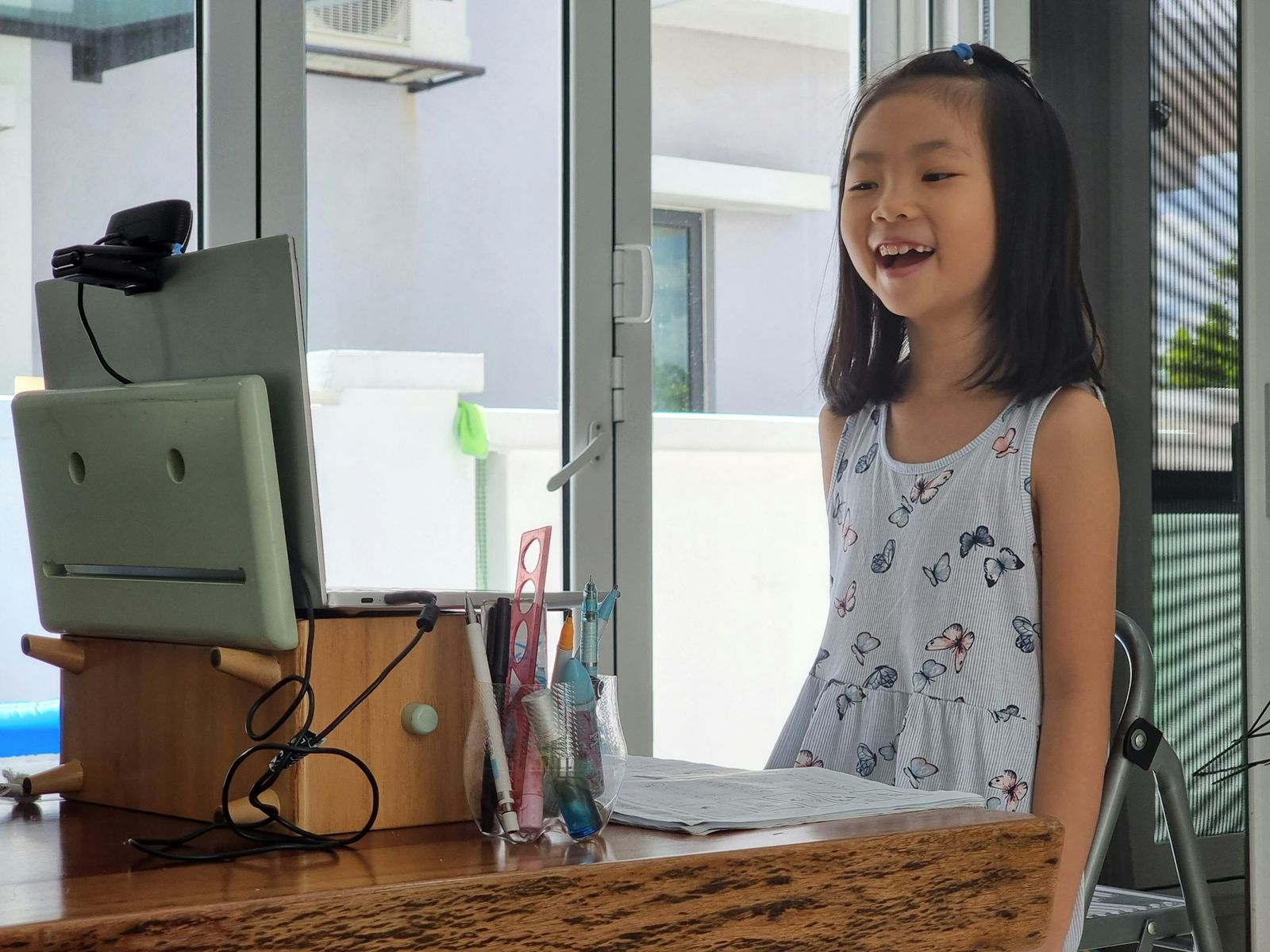 A girl smiling at her art lesson on a screen at home