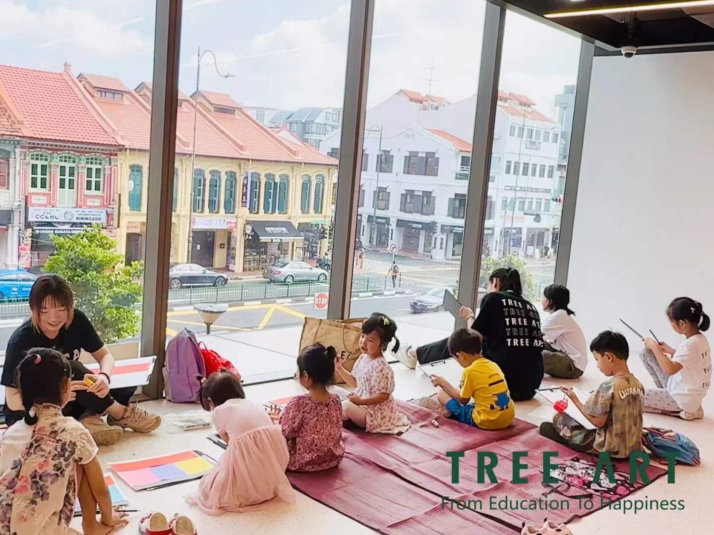 Children sitting on the floor sketching shophouse windows during an art class