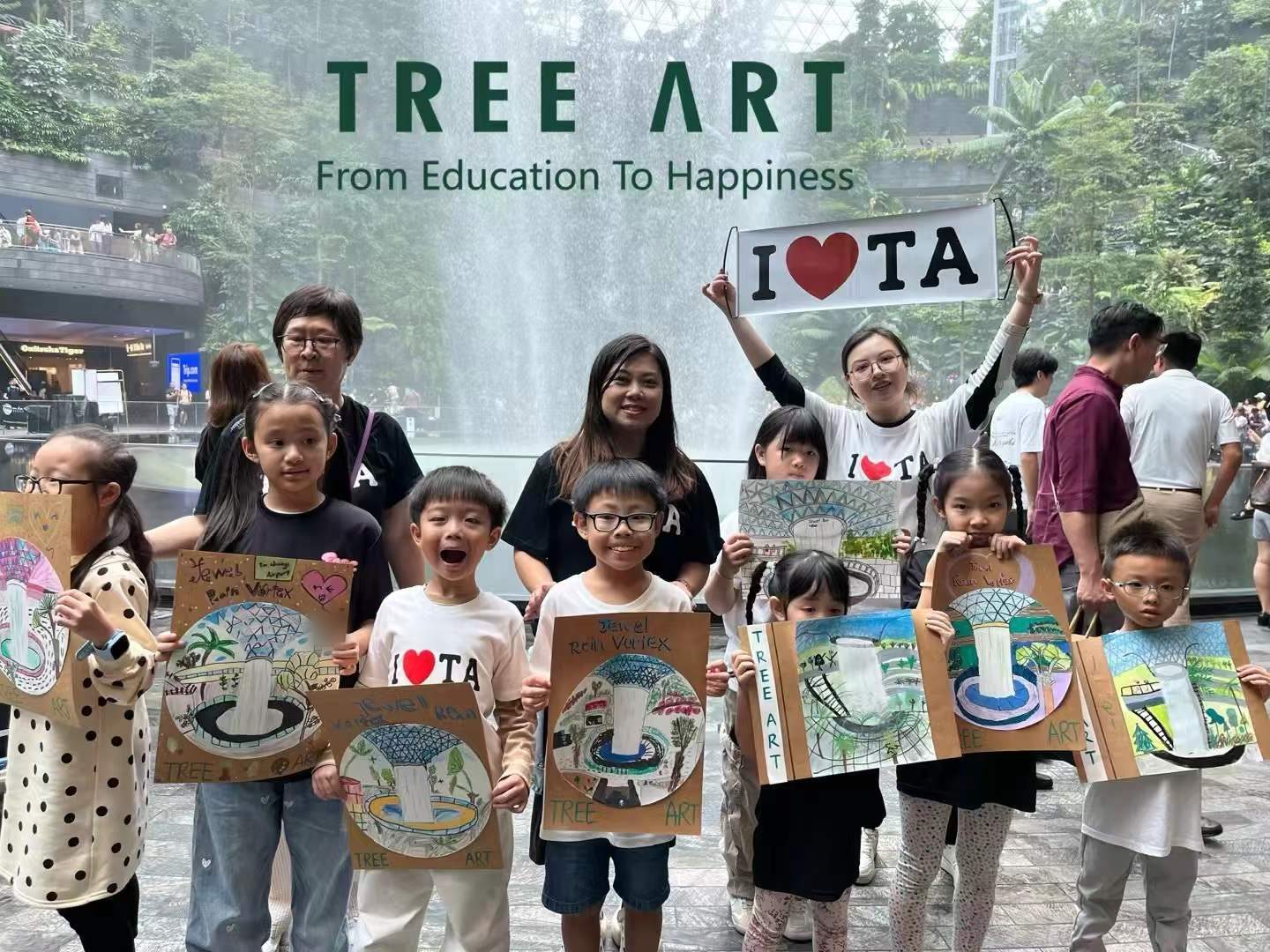 Students and teachers holding up their finished Rain Vortex paintings in front of the Jewel Changi waterfall