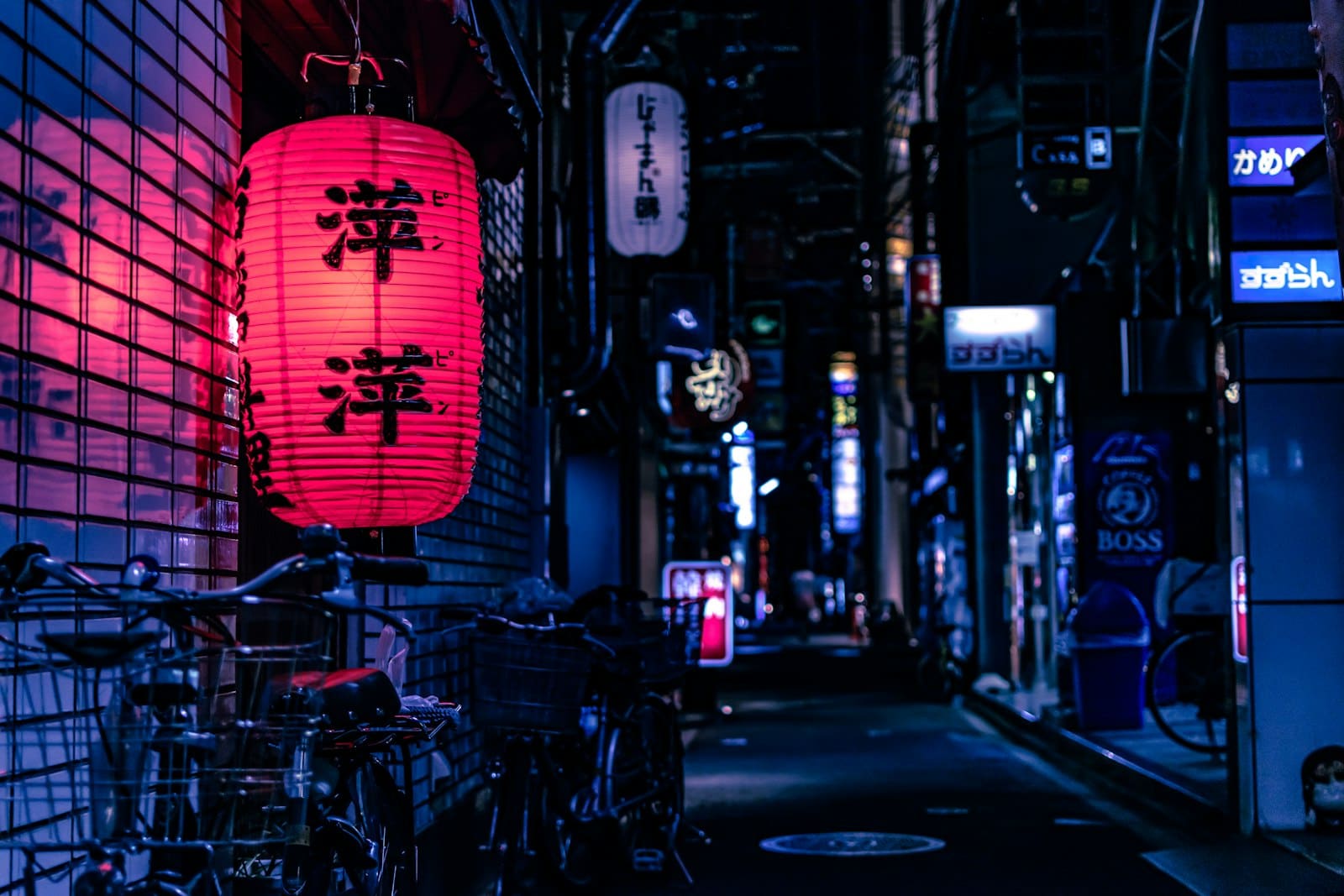 A red paper lantern glowing in a neon-lit Tokyo alley at night