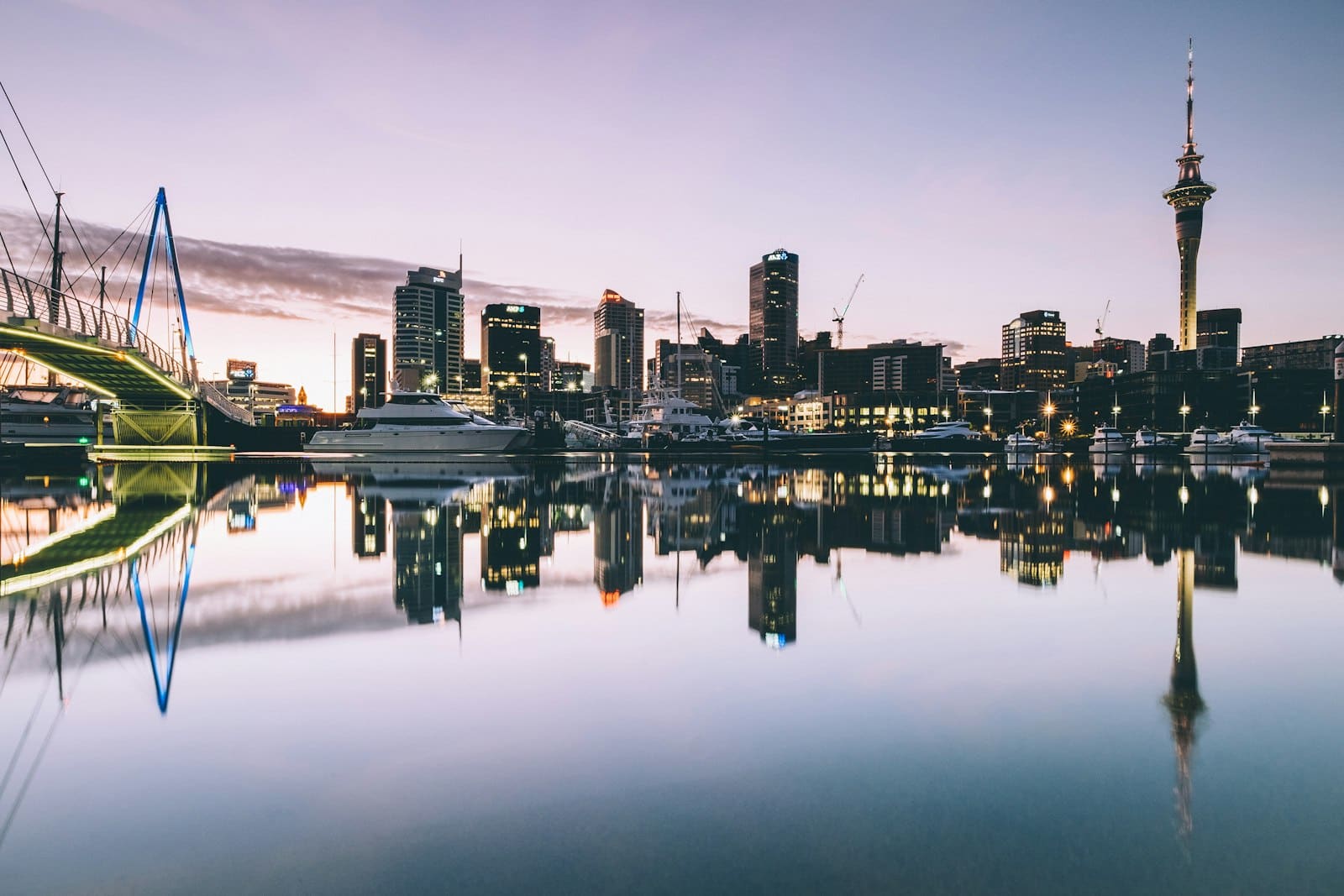 Auckland's skyline and Sky Tower reflected in still harbour water