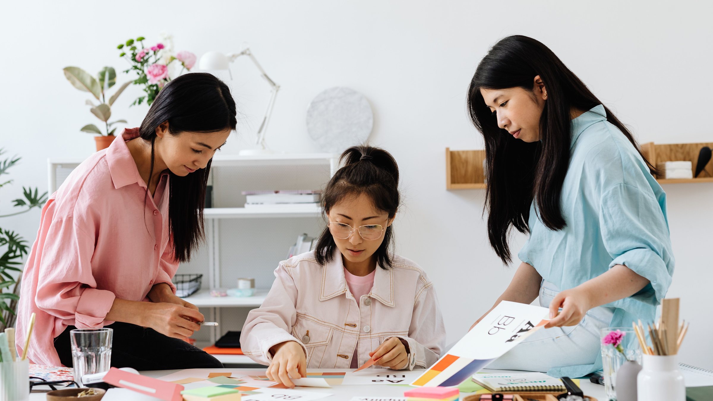 Three creatives planning a project together over papers and colour swatches at a studio table
