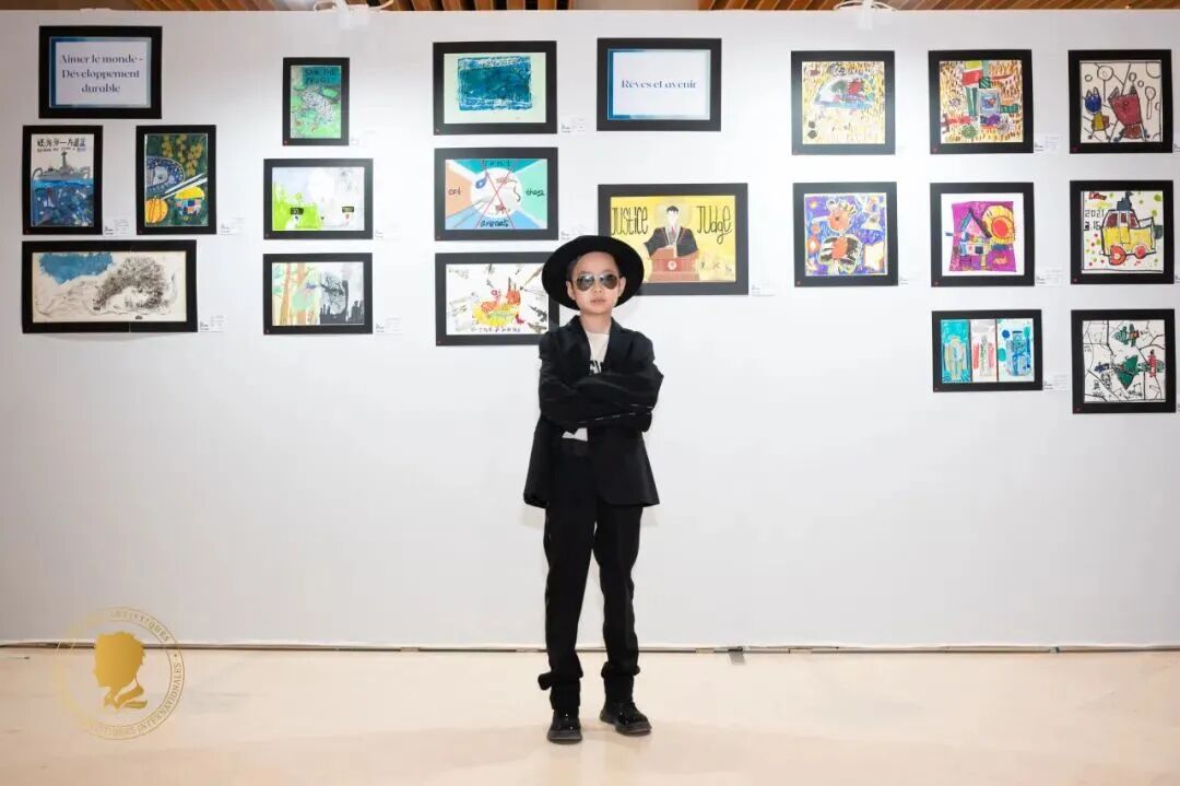 An artist in front of displayed artworks